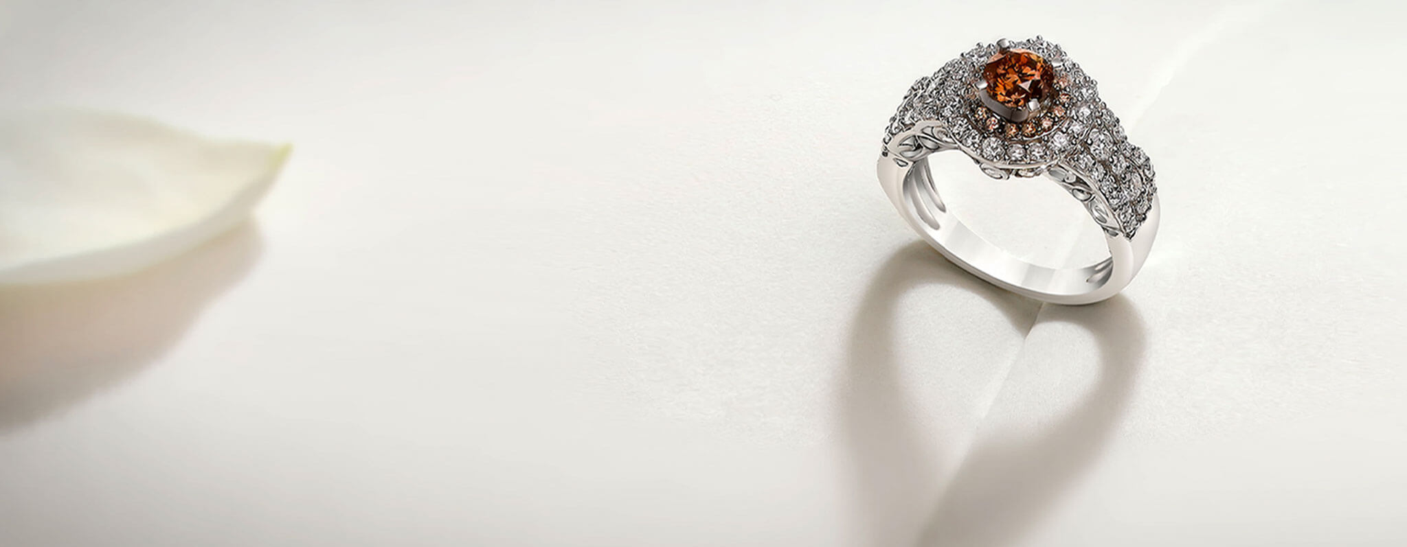 A Platinum Love Collection ring on a white surface with a heart-shaped shadow.